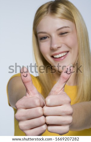 Young woman with happy face drawn on thumbs