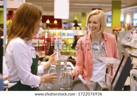 Customer returning glass bottles at the checkout of organic grocery store