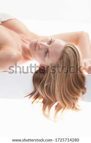 Mid adult woman lying on back in white lingerie, studio