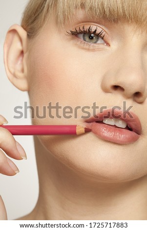 Portrait of young woman applying lip liner