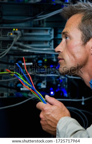 Close-up of computer technician holding colorful wires in server room in Cape Town, South Africa
