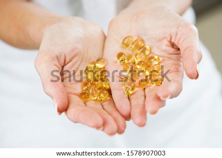 A woman holding a handful of vitamin supplement capsules