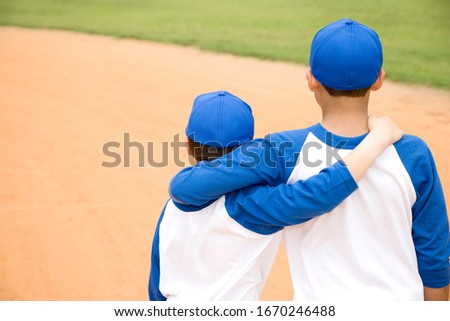 two boys walking away with arms around each other\'s shoulders