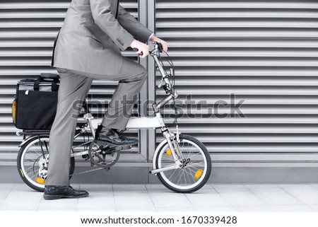 Close up of businessman cycling to work on folding commuter bicycle on pavement