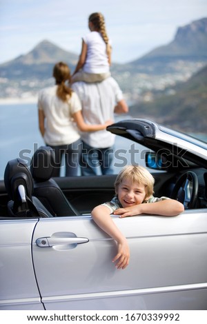 Family on road trip in convertible car looking at coastal scenery
