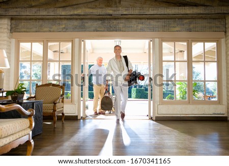 Two mature men in hotel foyer with golf bag and luggage
