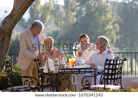 Mature couple with friends dining at outdoor restaurant table