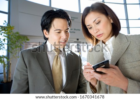 Businessman and businesswoman in airport using electronic organizer