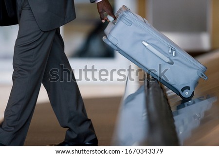 Businessman on trip taking suitcase from airport baggage carousel