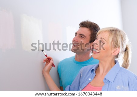 Couple decorating house painting test samples on wall
