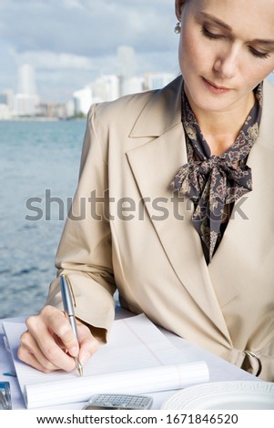 A businesswoman writing notes at waterfront