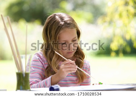 Young girl painting on a sunny day outside