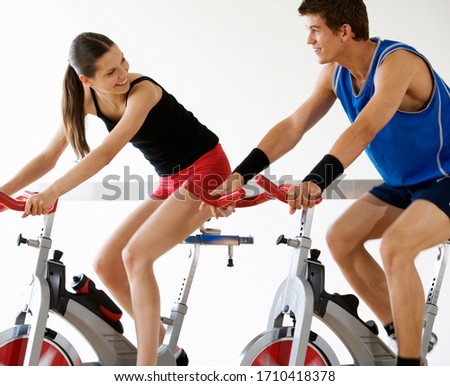 Two young people exercising on stationary bikes