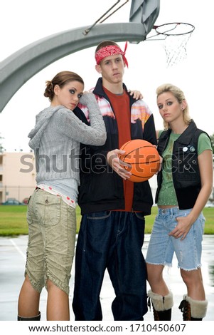 Three teenage friends posing on a basketball court