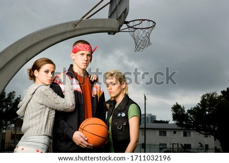 Three teenage friends hanging out on a basketball court