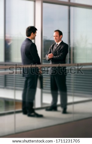 Two businessmen talking in an office hallway