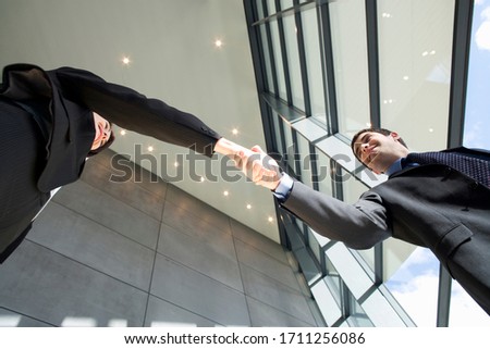 Business colleagues shaking hands in an office hallway