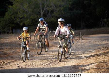 A family of four cycling on dirt track in countryside.