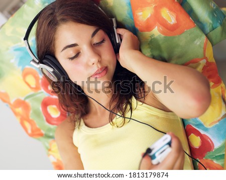 A female teenager listening to music through wired headphones.