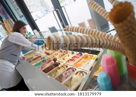 An angled view of a man serving in an ice cream parlor.
