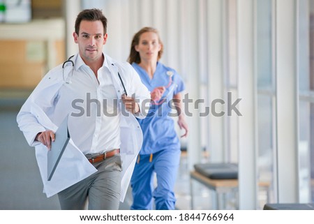 Doctor and nurse running down hospital corridor for an emergency case