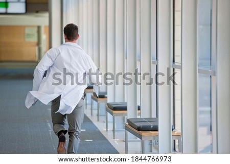 Doctor running down the hospital corridor with reports in hand