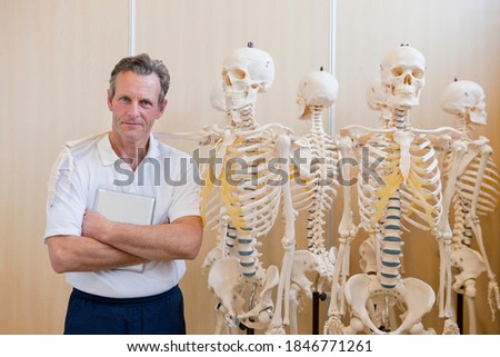 A sports scientist standing beside skeletons in a laboratory
