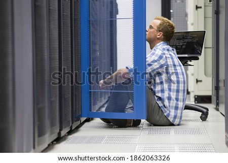 A technician sitting on the floor of a data center and analyzing the server