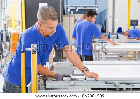 Wide shot of a technician working on the glass coating in a solar panel factory