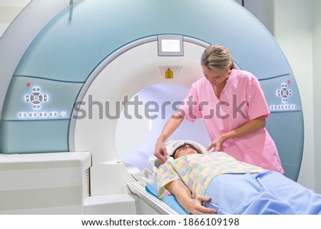 Wide shot of a technician nurse operating the MRI machine while the patient is laying on it