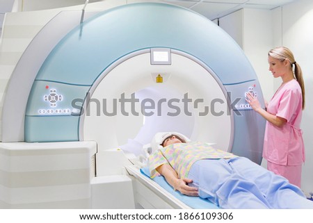 Technician nurse is operating the MRI machine while the patient is laying on it