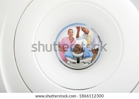 Wide shot of a doctor and nurse preparing a patient at the CT scanner tube in the hospital