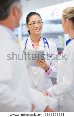 Vertical shot of a female doctor with a stethoscope and digital tablet standing next to her colleagues.