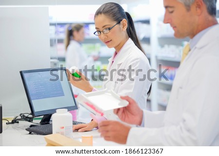 Portrait shot of a female pharmacist inspecting medicines at a pharmacy counter.