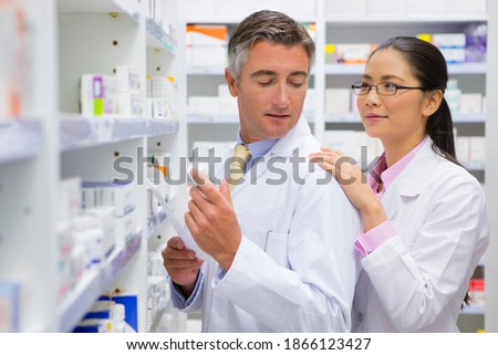 Female pharmacist placing her hand on a colleagues shoulder at a pharmacy.