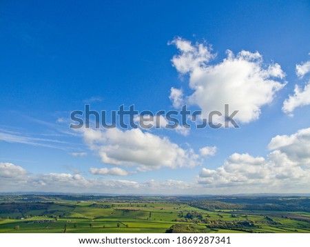 Scenic aerial view of green rolling landscape under the sunny blue sky with clouds