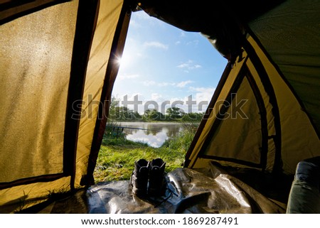 View from inside of the tent of fishing rod in the morning at lakeside