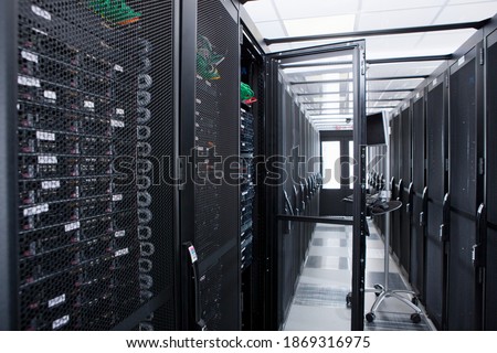 Aisle of a server room with cabinets and a portable computer.
