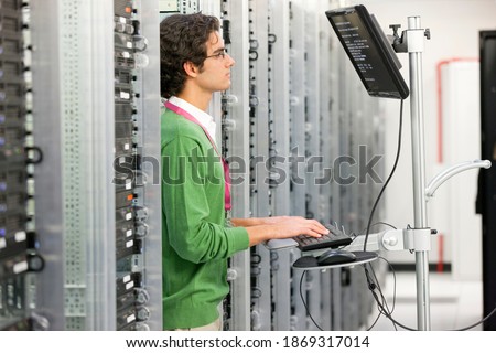 Side view of a technician working on a computer in the server room of a data center.