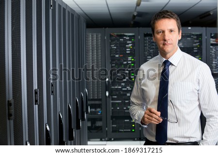 Portrait shot of a manager holding glasses standing in a server room.