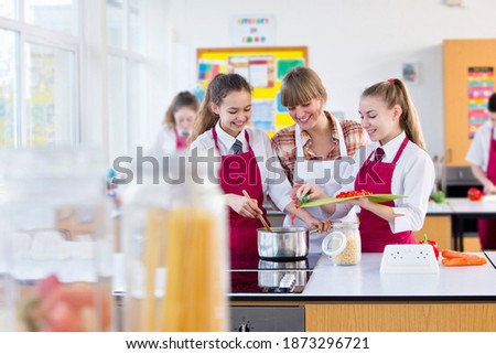 Teacher guiding her students while they cooks during a home economics class.