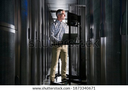 Wide shot of a Technician With a Laptop Working In the Secured Data Centre