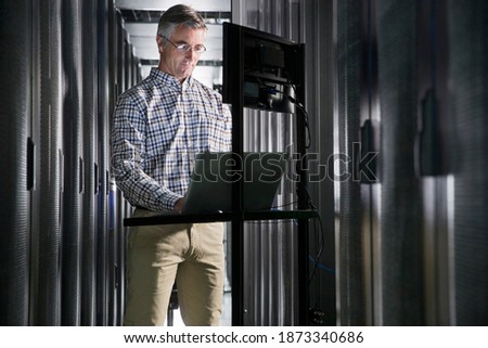 Technician With a Laptop Working In the Secured Data Centre
