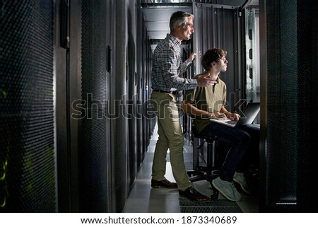 Wide shot of Two Technicians With a Laptop Working In the Secured Data Centre