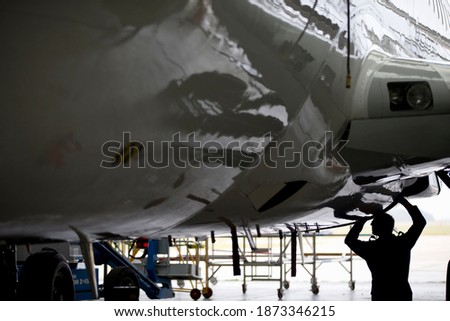Aircraft maintenance technician checking airplane for safety in airport hanger