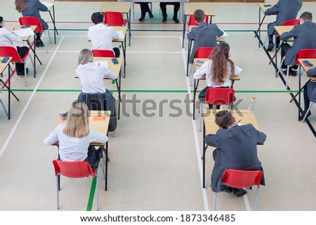 Middle school students taking examination at desks in school gymnastics hall