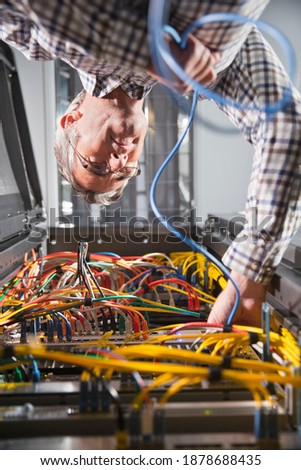 Low angle Vertical shot of a Technician Inspecting Server Wiring In the secured data center