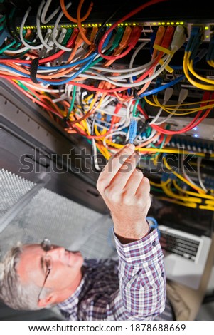 Close up of a cable being attached to the server by the technician
