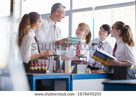 Chemistry teacher teaching high school students as they conduct a scientific experiment.