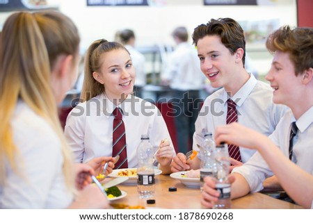 A group of high school students eating lunch in the school cafeteria.